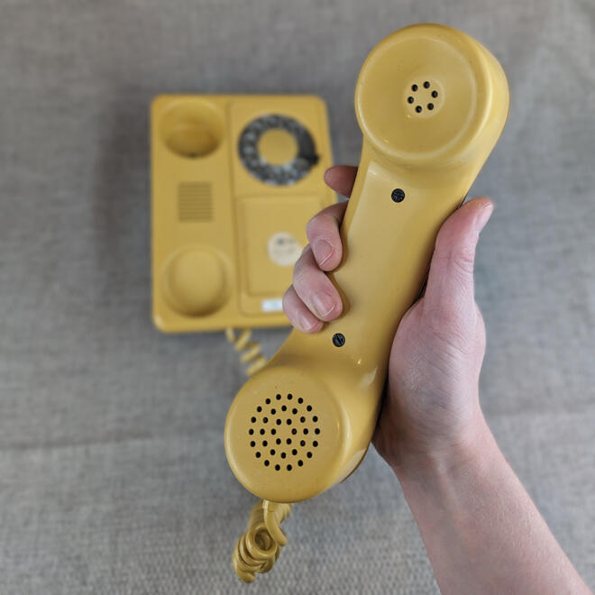 Yellow rotary phone being answered.